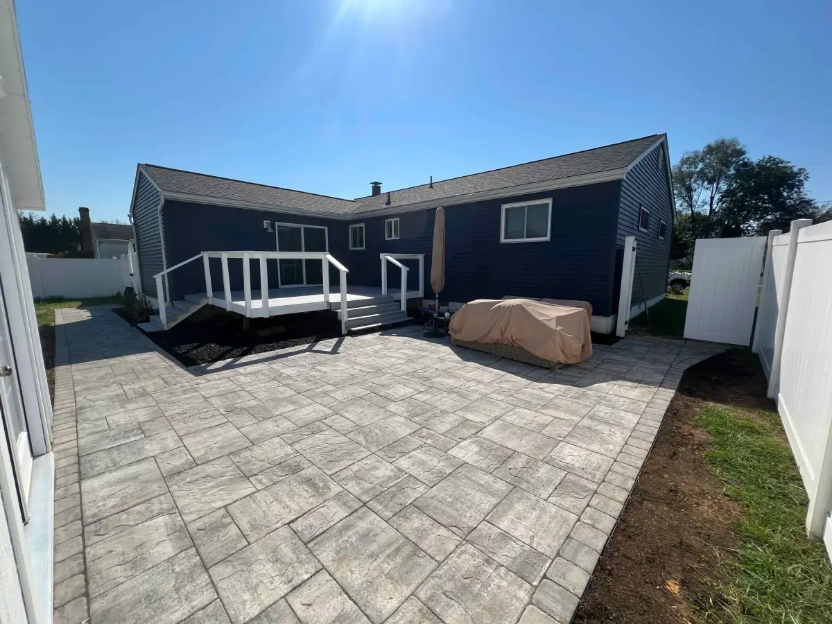 Finished paver patio beside a blue house and white deck, built by O. A. Thomas Landscaping